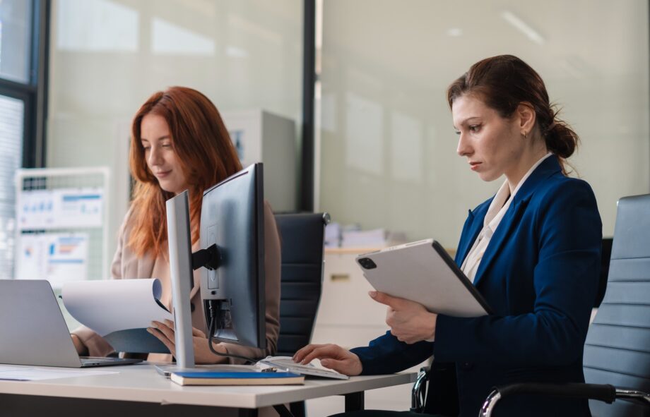 Two busy happy business woman executive leaders team using laptop working on computer at work desk having conversation on financial project at meeting in office.