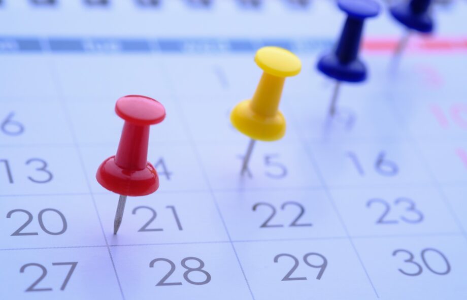 Brightly colored push pins are used to highlight important dates and events on a calendar